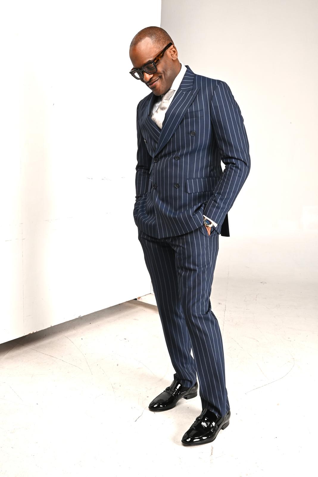 Dr. Glenn Toby looking down in a navy pinstripe suit